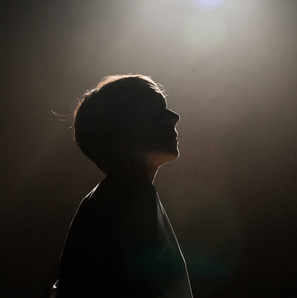 The silhouette of a woman with a light above her head.