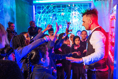 A school group raising their hands and interacting with an actor.