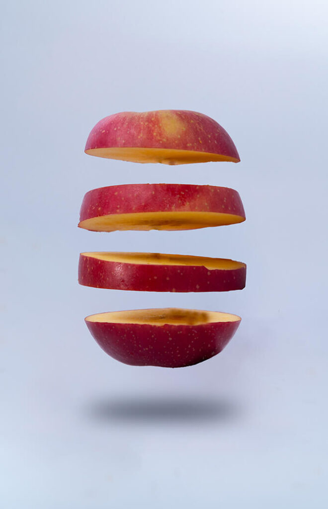 A segmented apple against a light grey background.