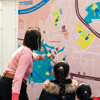 A woman and two young children stood with their backs to the camera, looking at a giant map of Washwood Heath and Ward End.