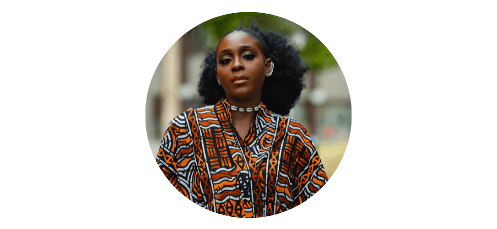 A woman with tied back afro hair. She is facing towards the camera, wearing a patterned blouse, shell necklace and cuff earring. She is looking directly at the camera smiling. Her photo is contained with a circular frame.