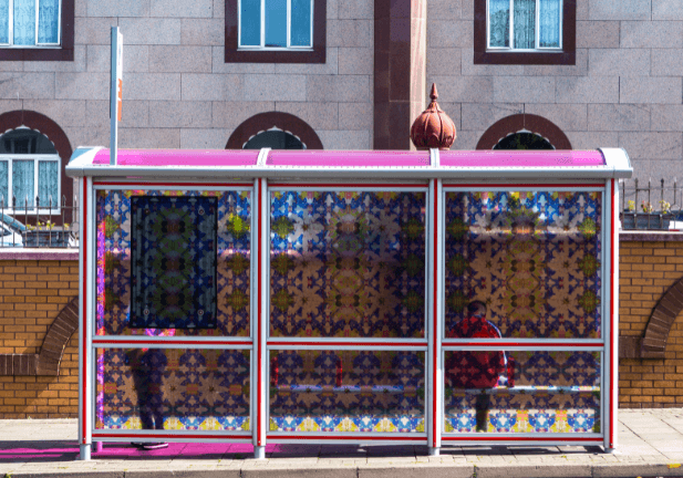hotograph of a bus stop outside a temple, decorated with stain glass style patterns.