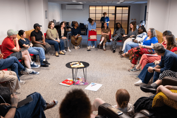 A large group of people sat round in a circle having a discussion.